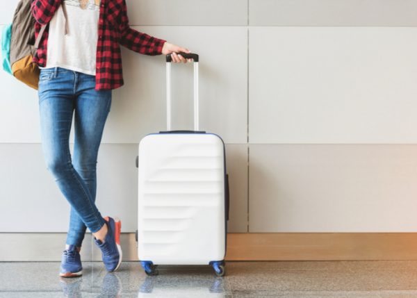 a woman in a flannel holding her luggage in the airport