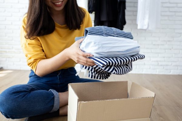 a woman placing her clothes in a cardboard box