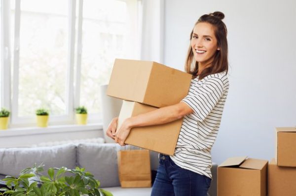 a woman carrying two cardboard boxes while moving